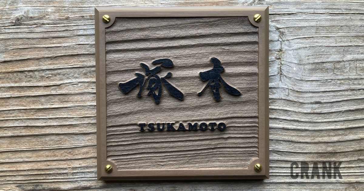 木目調の板に浮き彫りで仕上げた自筆文字の表札（塚本様）