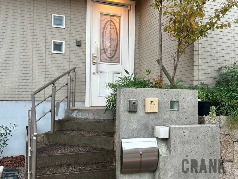 高耐久天然木材ACCOYA®を使用した、我が家と愛犬をモチーフにした木製表札。コンクリートの壁とインターホン、モダンな玄関階段。