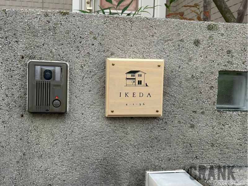 高耐久木材ACCOYA®を使用した木製表札の設置事例。コンクリートの門柱に表札とインターホン、ポストが設置されたモダンな玄関周りと階段。